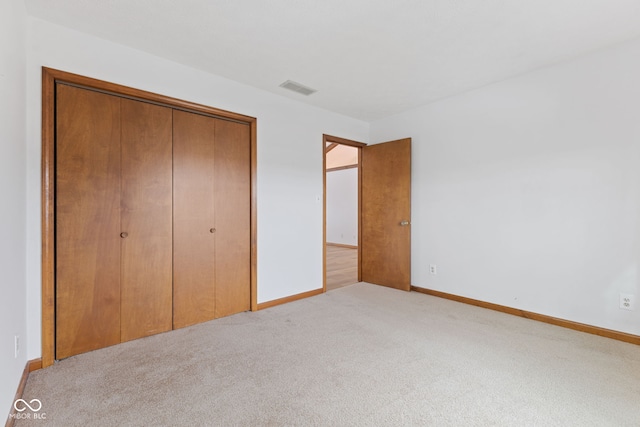 unfurnished bedroom with baseboards, a closet, visible vents, and light colored carpet