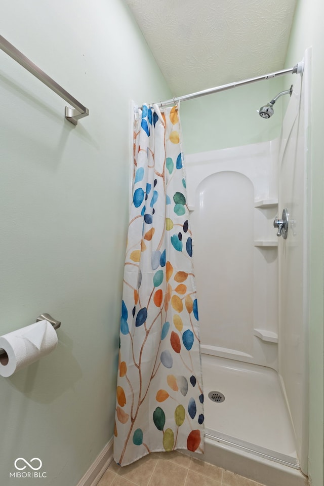 bathroom featuring tile patterned flooring, a shower stall, and a textured ceiling