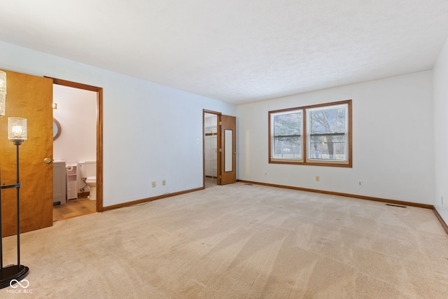 unfurnished room with visible vents, baseboards, a textured ceiling, and light colored carpet