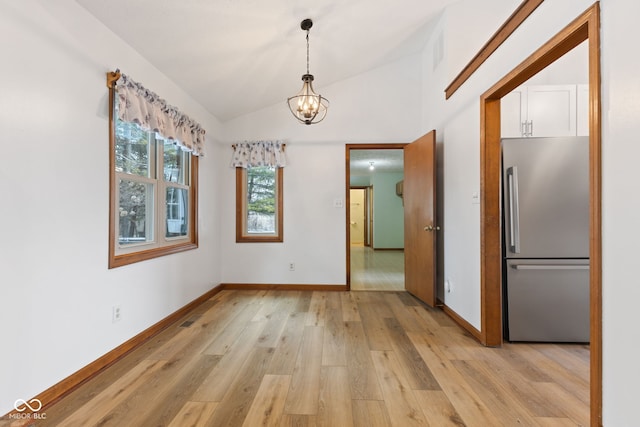 unfurnished dining area featuring light wood finished floors, visible vents, baseboards, lofted ceiling, and a chandelier