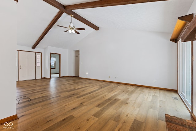 unfurnished living room featuring lofted ceiling with beams, light wood-style flooring, baseboards, and ceiling fan