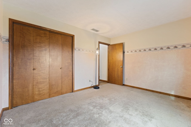 unfurnished bedroom featuring visible vents, baseboards, a closet, and light colored carpet