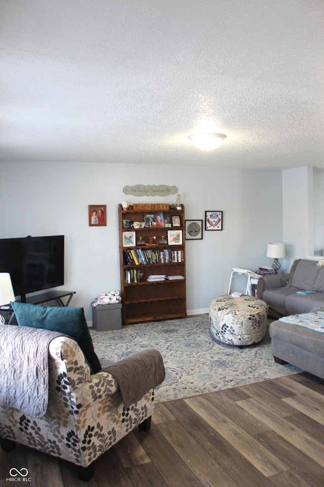 living room featuring a textured ceiling, baseboards, and wood finished floors