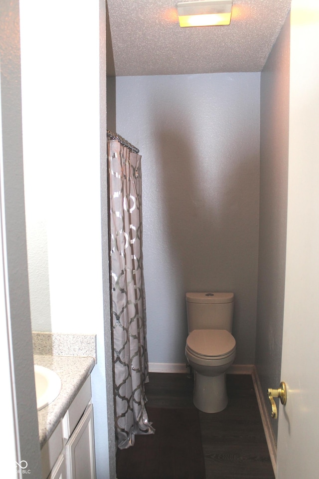 full bath with a textured ceiling, wood finished floors, vanity, and baseboards