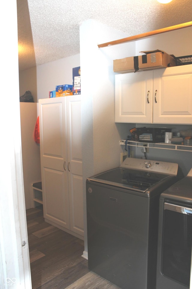 laundry area featuring dark wood-style floors, a textured ceiling, independent washer and dryer, and cabinet space