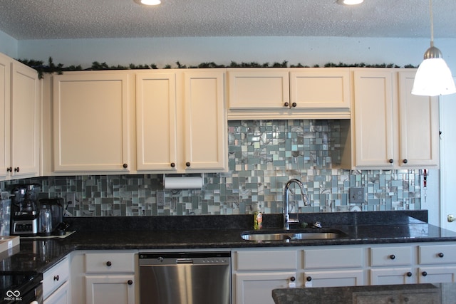 kitchen featuring hanging light fixtures, stainless steel dishwasher, white cabinetry, a sink, and dark stone counters