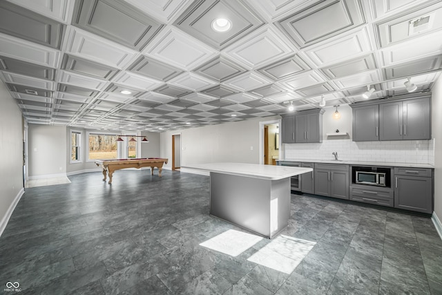 kitchen with gray cabinetry, baseboards, light countertops, tasteful backsplash, and stainless steel microwave