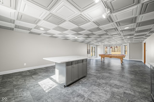 interior space with a center island, baseboards, open floor plan, gray cabinets, and light stone countertops