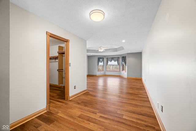 interior space with recessed lighting, a ceiling fan, a textured ceiling, wood finished floors, and baseboards