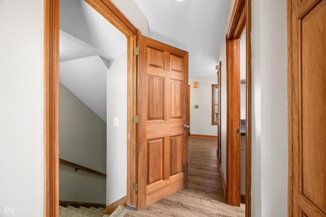 hall with light wood-style floors and baseboards