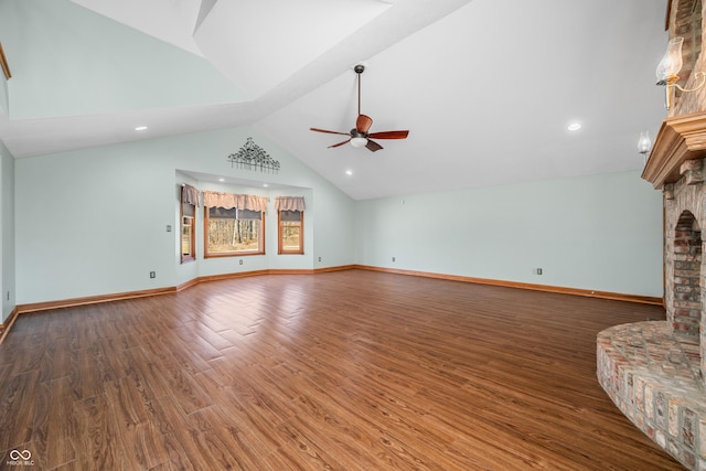 unfurnished living room with ceiling fan, high vaulted ceiling, a fireplace, wood finished floors, and baseboards