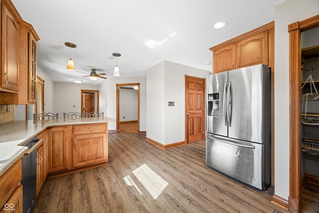 kitchen featuring a peninsula, appliances with stainless steel finishes, brown cabinets, and light wood-style floors