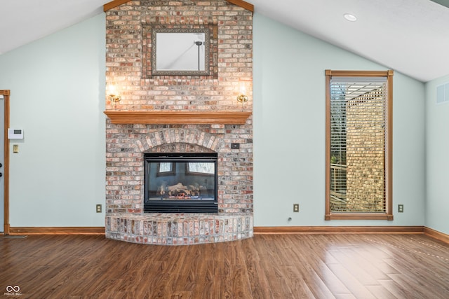 unfurnished living room with a brick fireplace, baseboards, vaulted ceiling, and wood finished floors