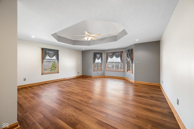 empty room featuring baseboards, a raised ceiling, ceiling fan, hardwood / wood-style floors, and recessed lighting