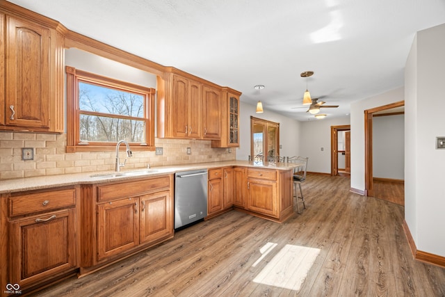 kitchen with tasteful backsplash, dishwasher, a peninsula, a kitchen bar, and a sink