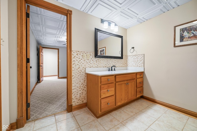 bathroom with an ornate ceiling, baseboards, tile patterned flooring, and vanity