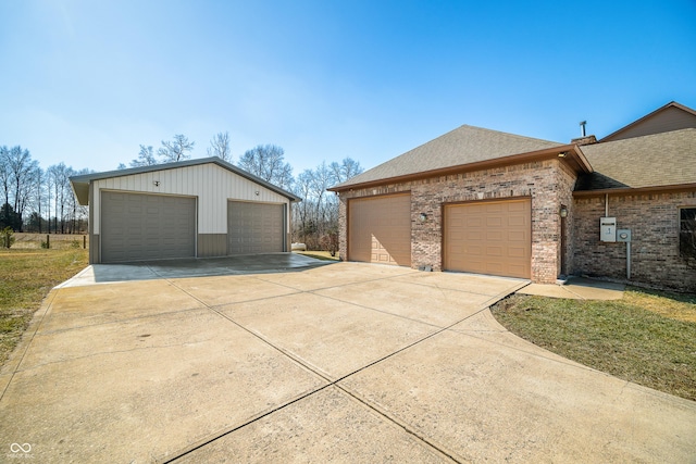 view of home's exterior featuring roof with shingles, a detached garage, and brick siding