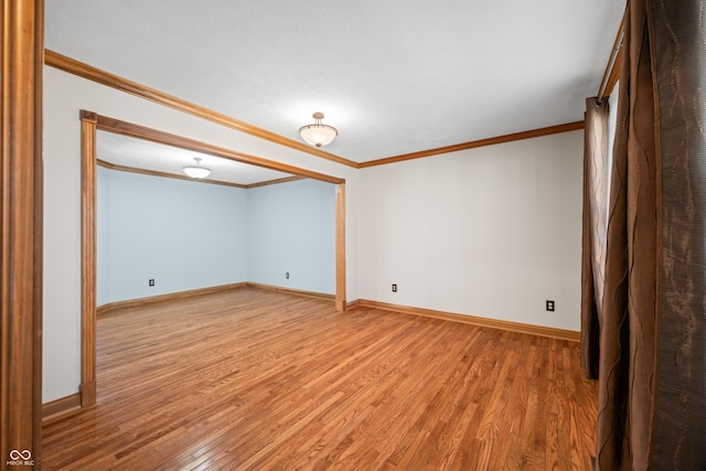 unfurnished room featuring crown molding, baseboards, and wood finished floors