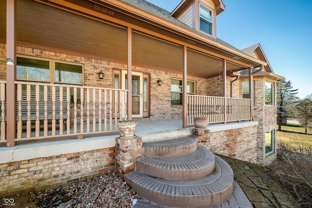 view of exterior entry with covered porch and brick siding