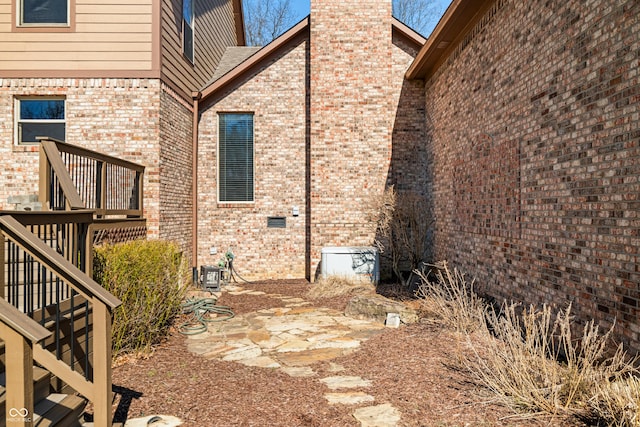 exterior space featuring brick siding, stairway, and a chimney