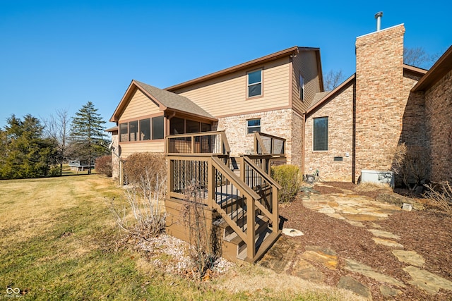 back of house featuring a sunroom, a yard, a chimney, and stairs