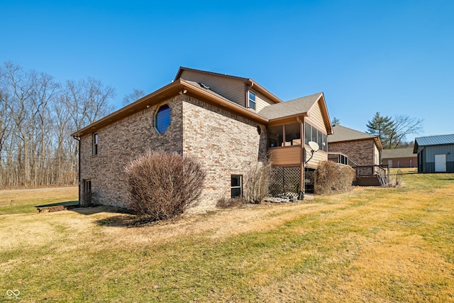 view of side of home featuring brick siding, a lawn, and a sunroom