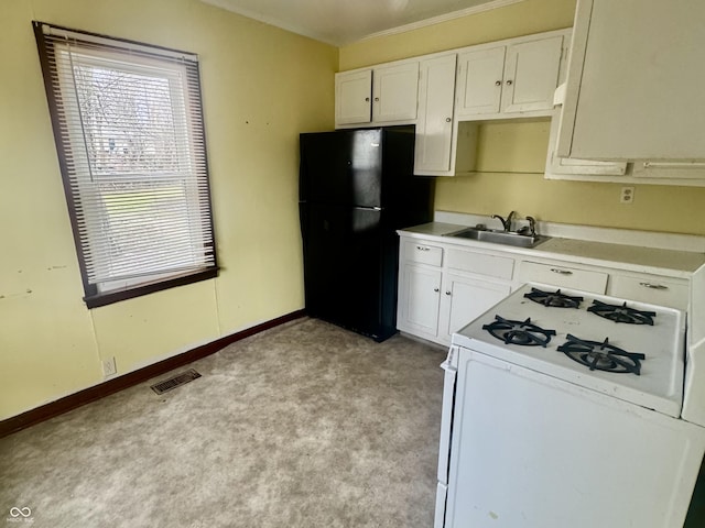 kitchen featuring white range with gas cooktop, visible vents, freestanding refrigerator, light countertops, and a sink