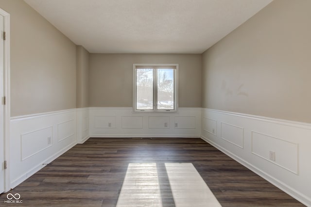 empty room with dark wood-style floors and wainscoting