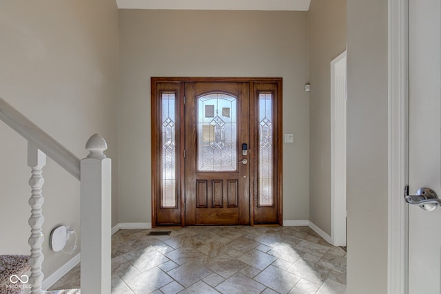 foyer with baseboards, stairway, and stone tile floors