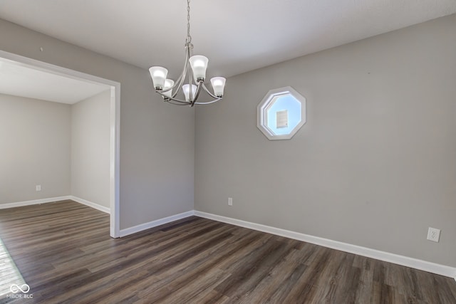 empty room with a notable chandelier, baseboards, and dark wood-style flooring