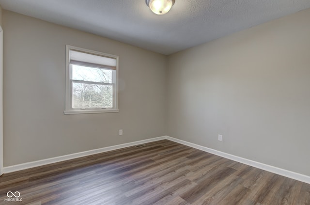 unfurnished room with a textured ceiling, baseboards, and dark wood-style flooring