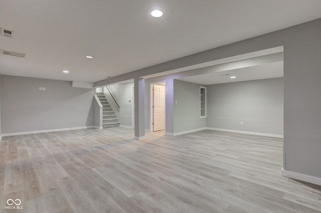 finished basement with recessed lighting, visible vents, baseboards, stairs, and light wood-type flooring