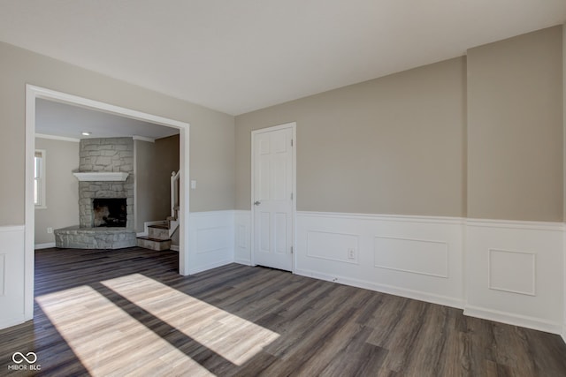 empty room with wainscoting, dark wood-type flooring, and a fireplace