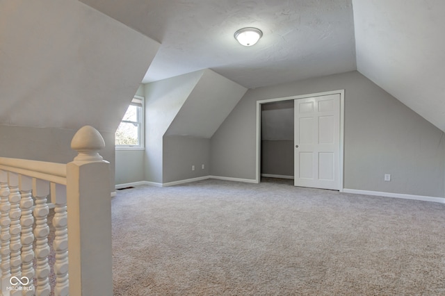 bonus room with light carpet, lofted ceiling, and baseboards