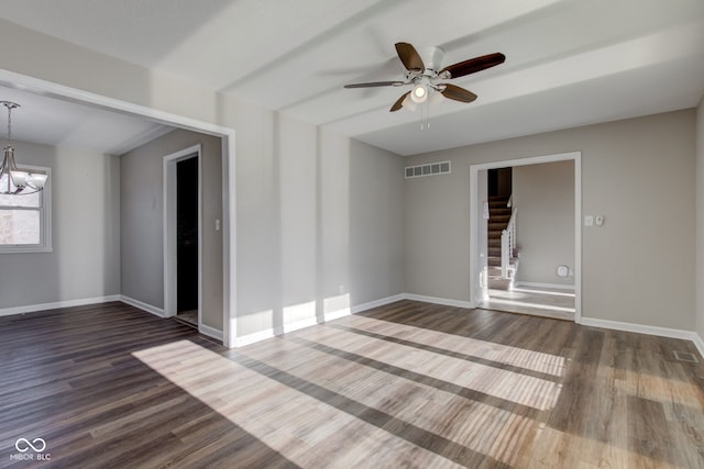 spare room with baseboards, visible vents, stairway, dark wood-style flooring, and ceiling fan with notable chandelier