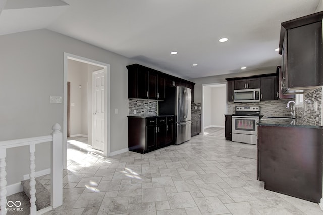 kitchen featuring tasteful backsplash, appliances with stainless steel finishes, a sink, dark brown cabinets, and baseboards