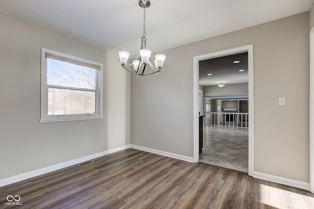 spare room with dark wood-style floors, visible vents, a notable chandelier, and baseboards