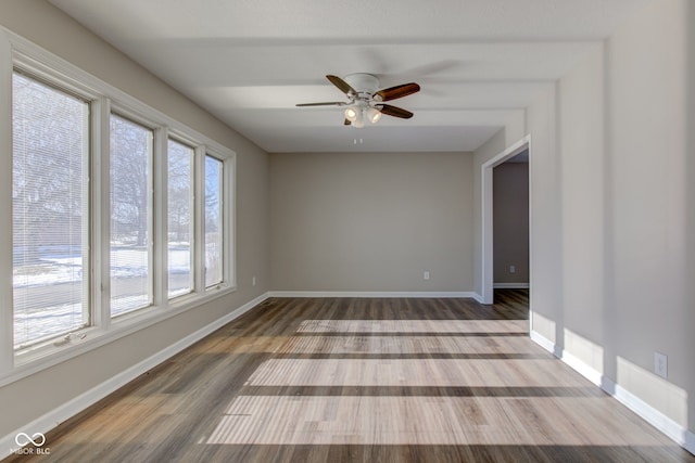 spare room with a ceiling fan, visible vents, baseboards, and wood finished floors