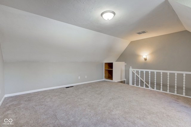 additional living space with lofted ceiling, visible vents, and carpet flooring