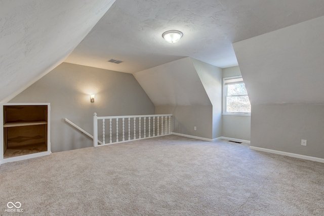 bonus room featuring carpet floors, visible vents, and a textured ceiling