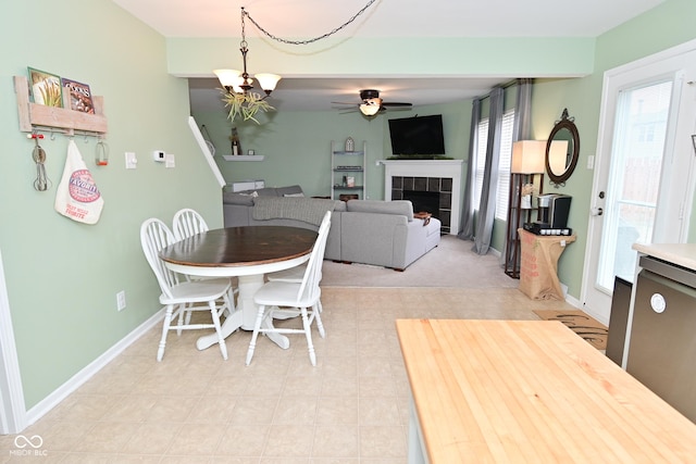 dining area with a fireplace, baseboards, and ceiling fan with notable chandelier