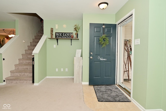 carpeted entryway with stairway and baseboards