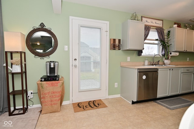 kitchen featuring baseboards, dishwasher, gray cabinets, light countertops, and a sink