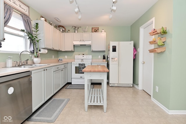 kitchen featuring under cabinet range hood, white appliances, butcher block countertops, a sink, and baseboards