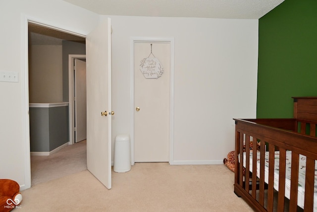 carpeted bedroom with a nursery area and baseboards