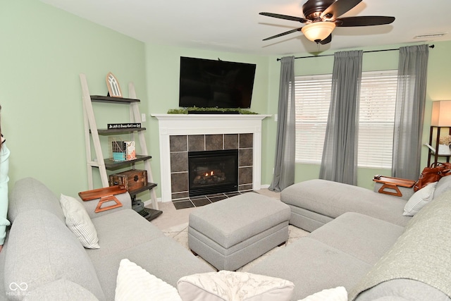 living area with baseboards, visible vents, a tiled fireplace, ceiling fan, and carpet flooring