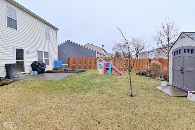 view of yard featuring a fenced backyard, a storage unit, an outdoor structure, a patio area, and a playground