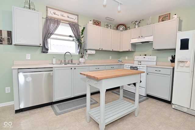 kitchen with white appliances, light countertops, a sink, and under cabinet range hood