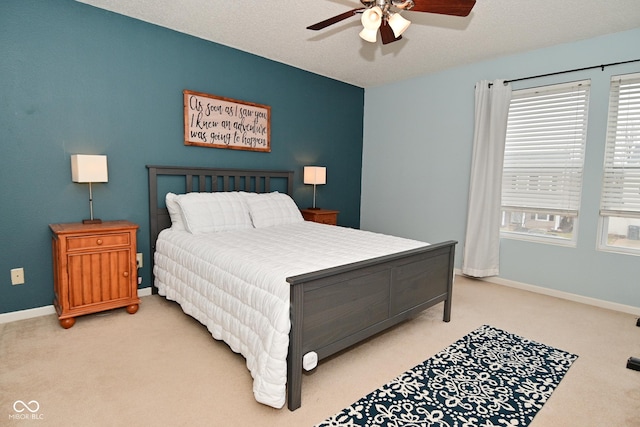 bedroom featuring a ceiling fan, light carpet, a textured ceiling, and baseboards