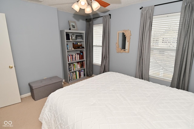 carpeted bedroom with ceiling fan and a textured ceiling